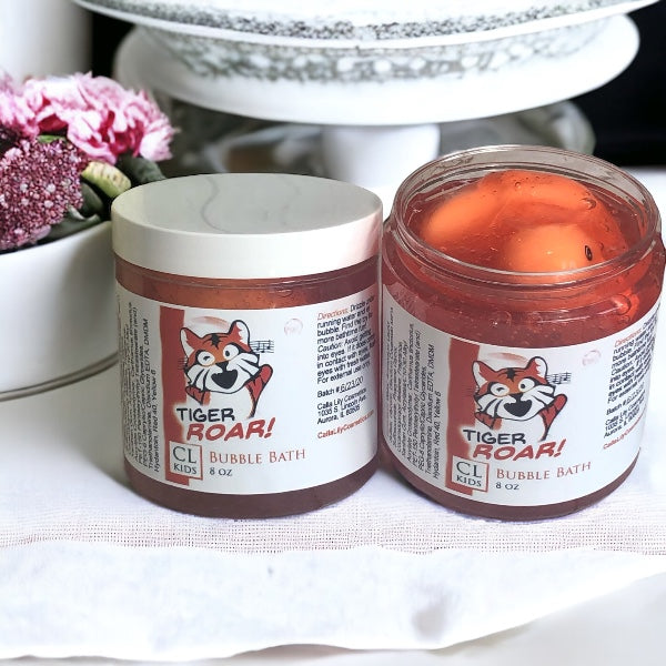 Two jars of Tiger Roar bubble bath on a white surface with flowers in the background.