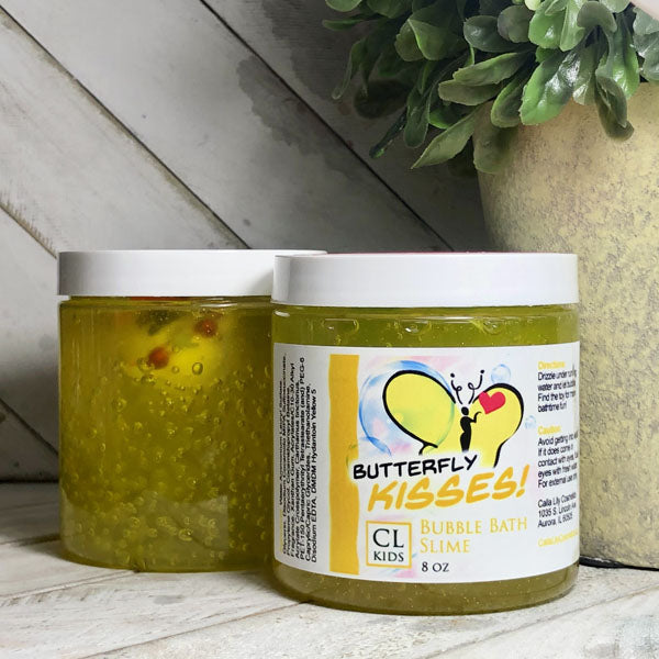 Jar of 'Butterfly Kisses' bubble bath slime with a visible label on a wooden surface.