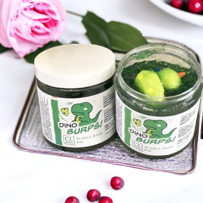 Two jars of Dino Burps! bubble bath with a pink flower and red berries in the background.