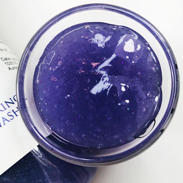 Unicorn Yawns Shimmering Body Wash in a cup of our purple unicorn yawns body wash against a white background