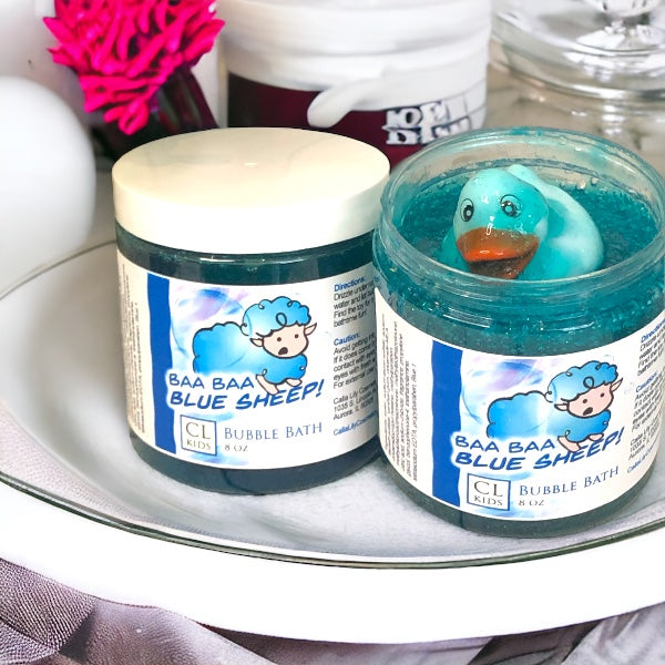 Two jars of 'Baa Baa Blue Sheep' bubble bath on a glass surface with a toy duck inside one jar.