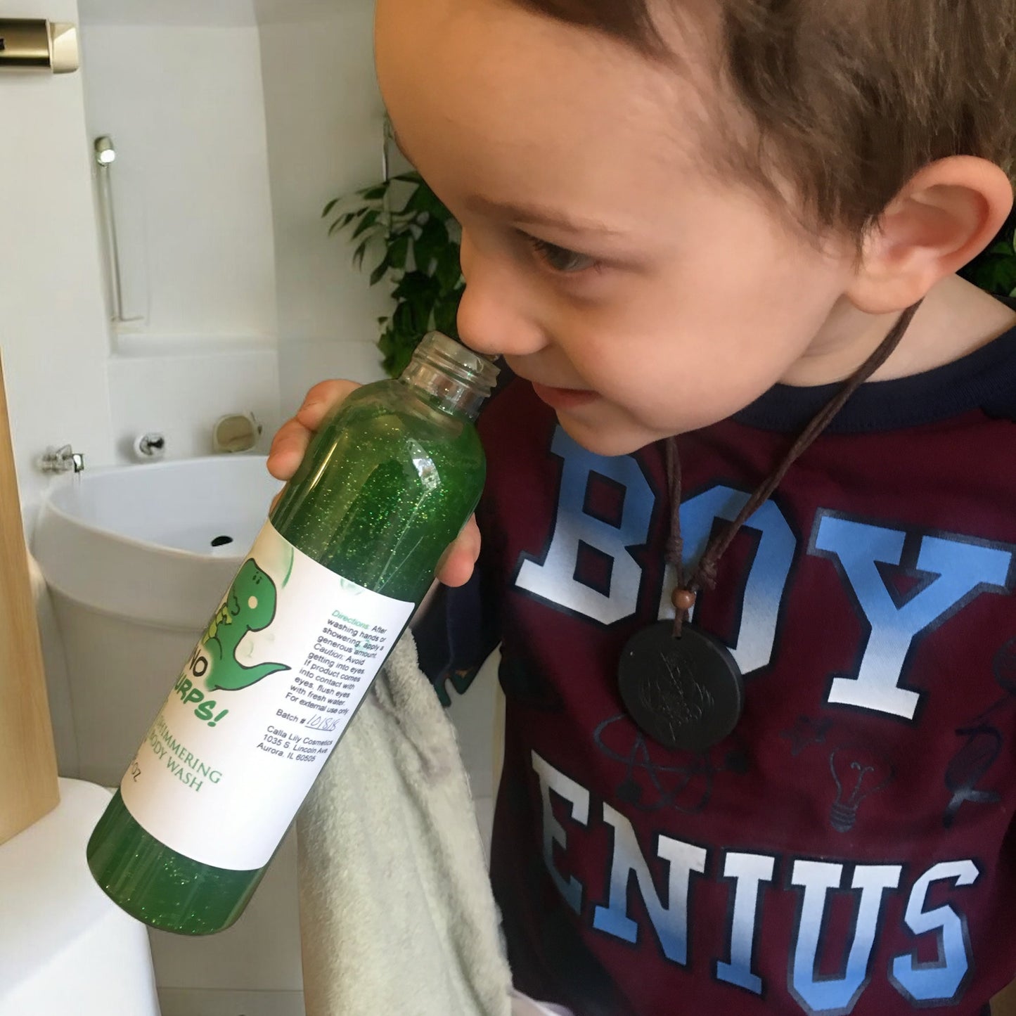 Dino Burps Shimmering Body Wash and a child holding a green bottle labeled 'Boys' in a bathroom setting