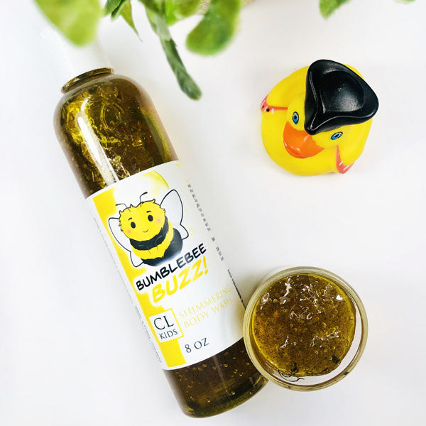 Bumblebee Buzz Shimmering Body Wash in a transparent bottle and cup of our golden yellow bumblebee buzz body wash against a white background