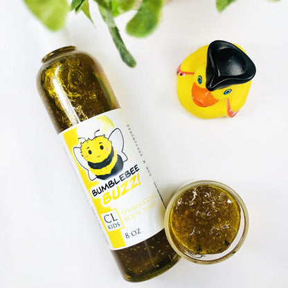 Bumblebee Buzz Shimmering Body Wash in a transparent bottle and cup of our golden yellow bumblebee buzz body wash against a white background