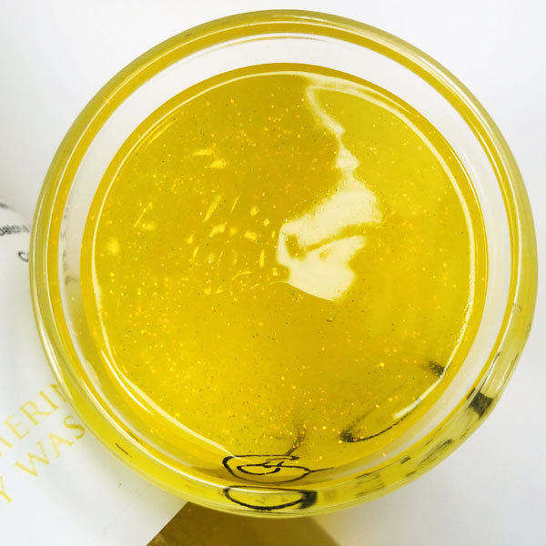 Butterfly Kisses Shimmering Body Wash in a cup of our yellow butterfly kisses body wash against a white background