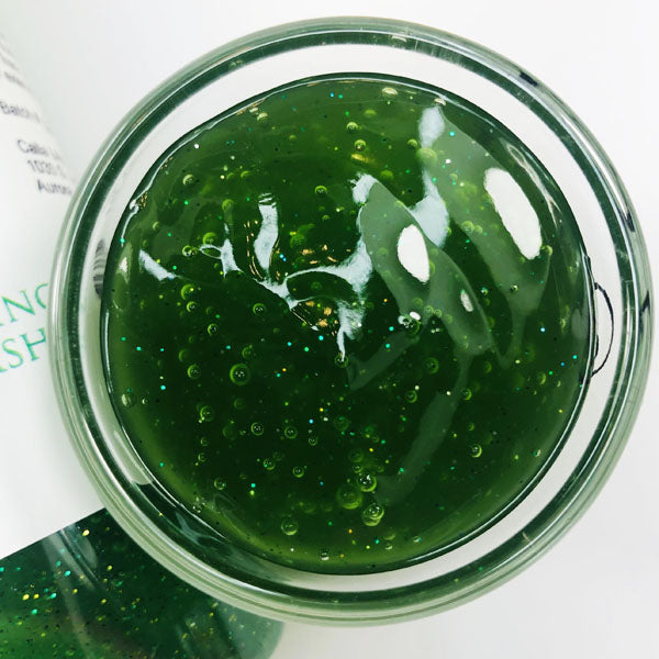 Dino Burps Shimmering Body Wash in a cup of our green dino burps body wash against a white background