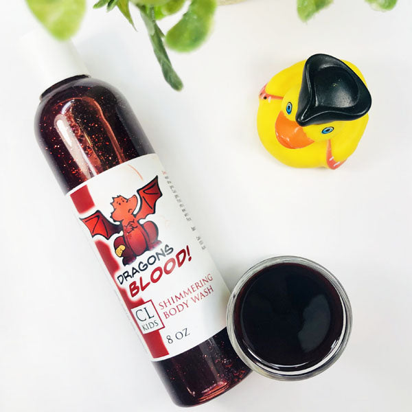 Dragons Blood Shimmering Body Wash in a transparent bottle and cup of our dark red dragons blood body wash against a white background