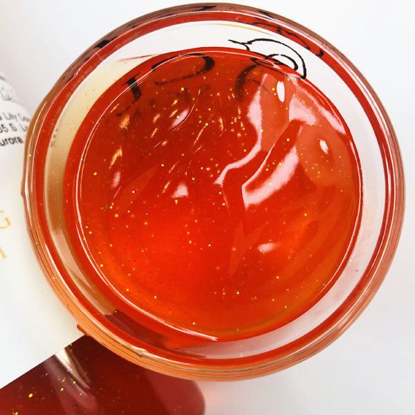 Monkey Farts Shimmering Body Wash in a cup of our orange monkey farts body wash against a white background