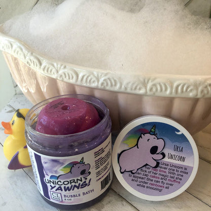 Jar of unicorn-themed bubble bath with a purple scoop and decorative container in the background.