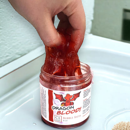 Jar of 'Dragon Blood' bubble bath with a hand lifting a piece of red bubble bath out of the jar.